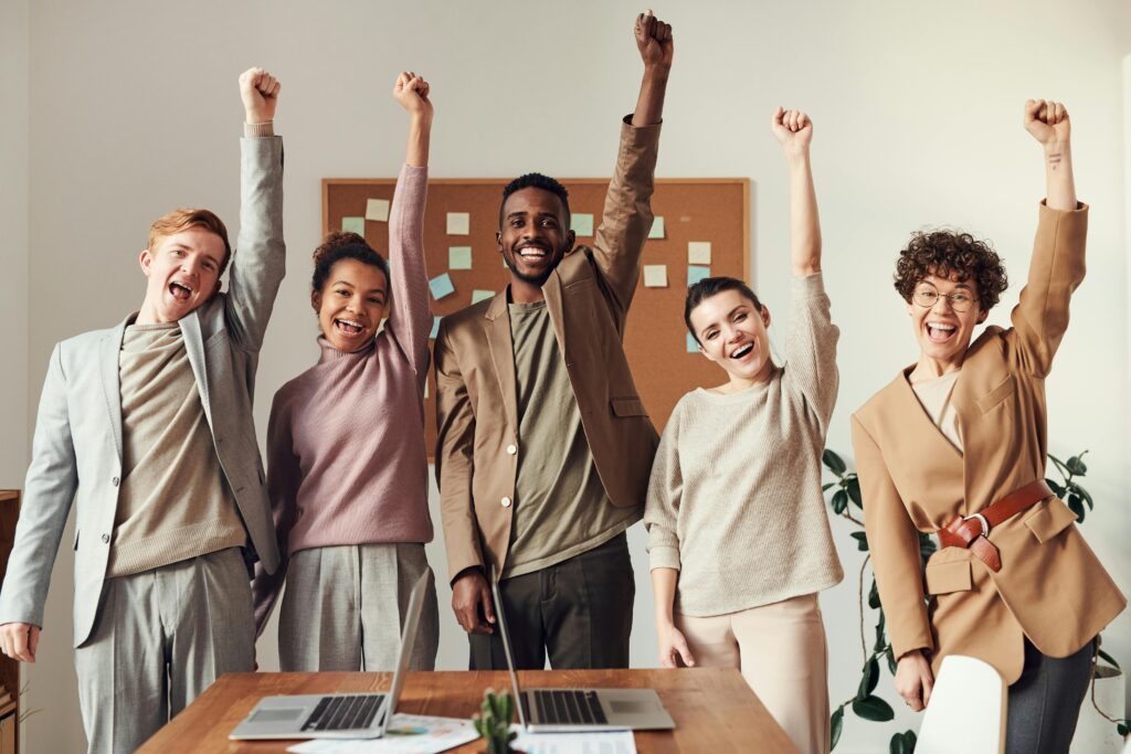 pexels photo 3184419 3184419 A diverse team celebrating success with raised hands in a modern office setting.