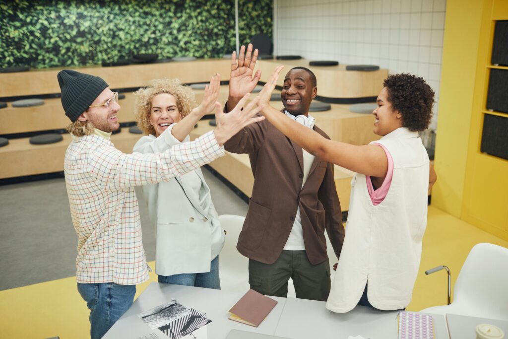pexels photo 7495191 7495191 A group of diverse colleagues in business attire celebrating with a high five indoors.
