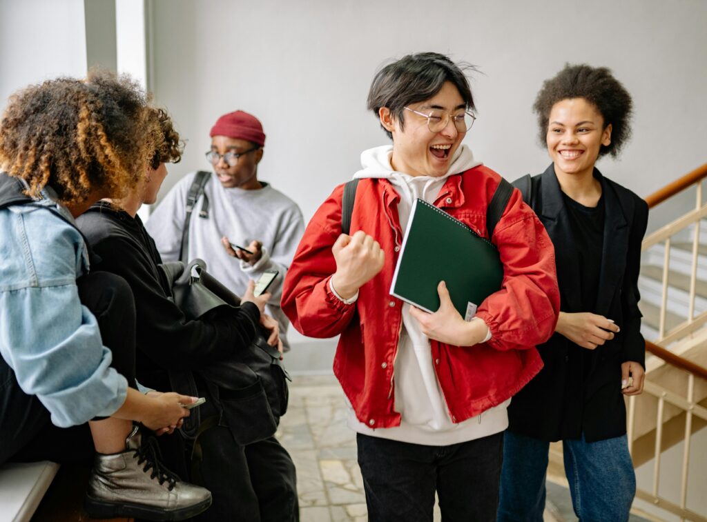 pexels photo 8199169 8199169 A group of diverse college students happily interacting indoors, showcasing friendship and diversity in a university setting.
